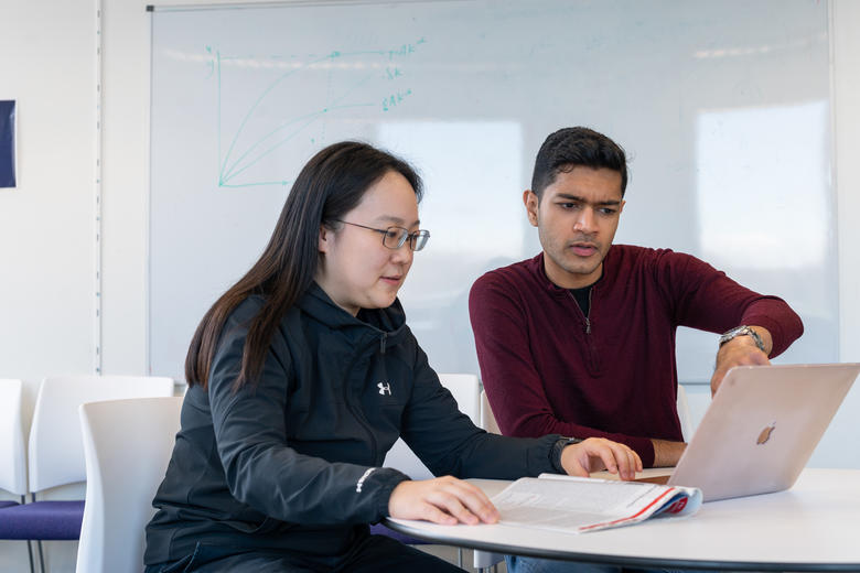 Two students discuss what is on a computer screen
